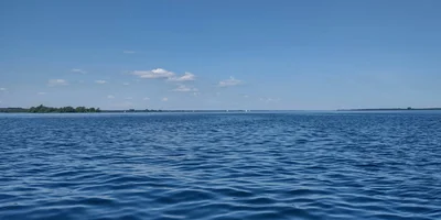 Calm blue waters of Lake Bonavista in Calgary with clear sky and distant shoreline, showcasing lakeside living appeal.