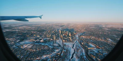 Aerial view of Calgary skyline from airplane window, symbolizing newcomers moving to the city in 2025.