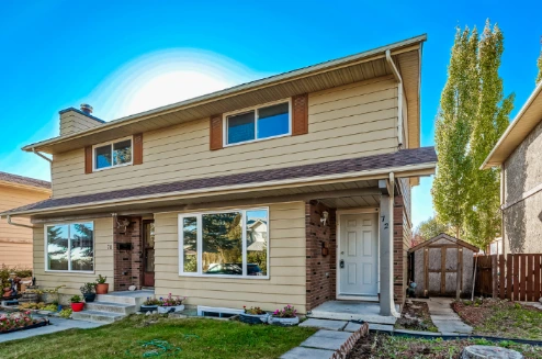 Front view of 72 Strathcona Crescent SW, Calgary semi-detached home for sale with landscaped yard and private entrance.
