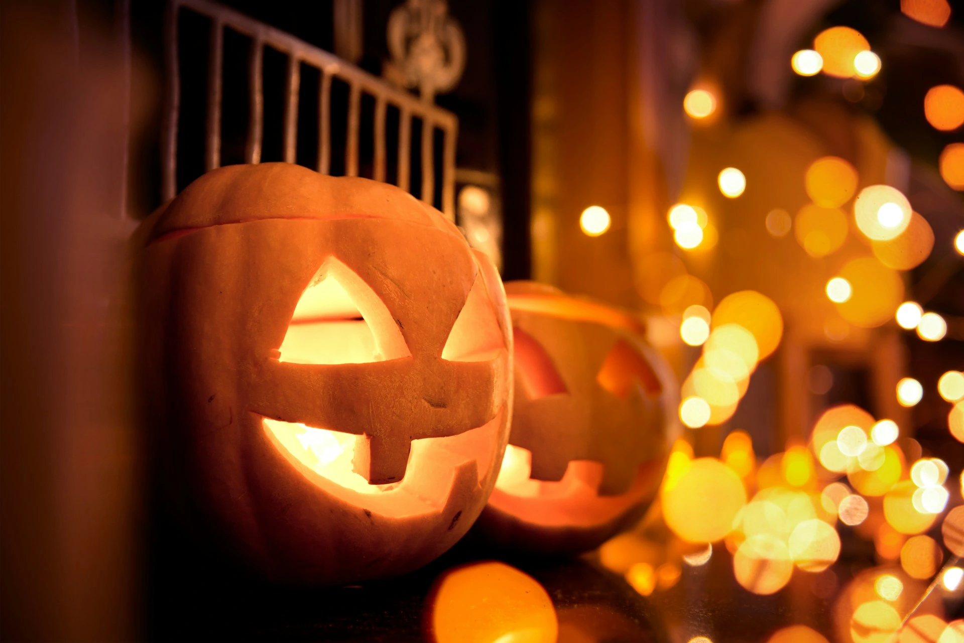 Carved jack-o’-lanterns glowing with string lights on a Calgary porch at night.