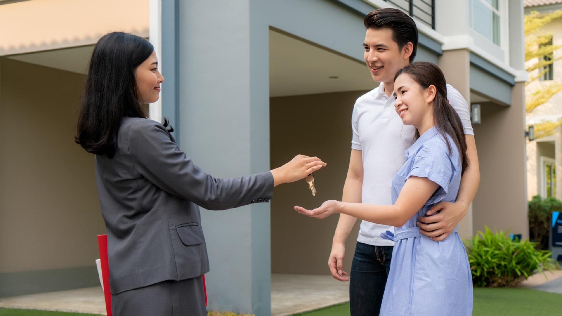 Real estate agent handing house keys to a happy couple after closing on their Calgary home