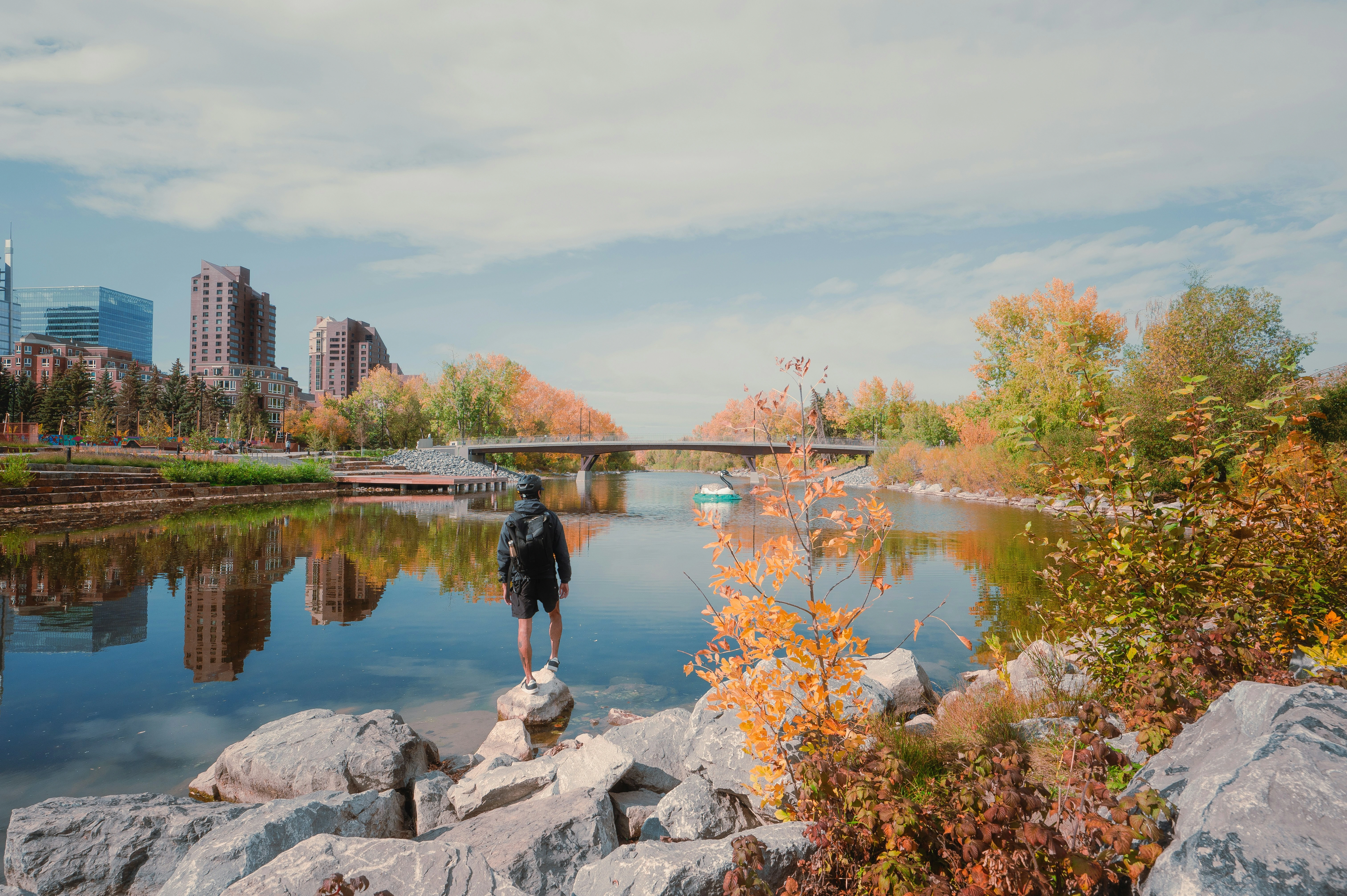 Person standing by Calgary’s Bow River surrounded by fall colors, representing Calgary’s autumn real estate market.