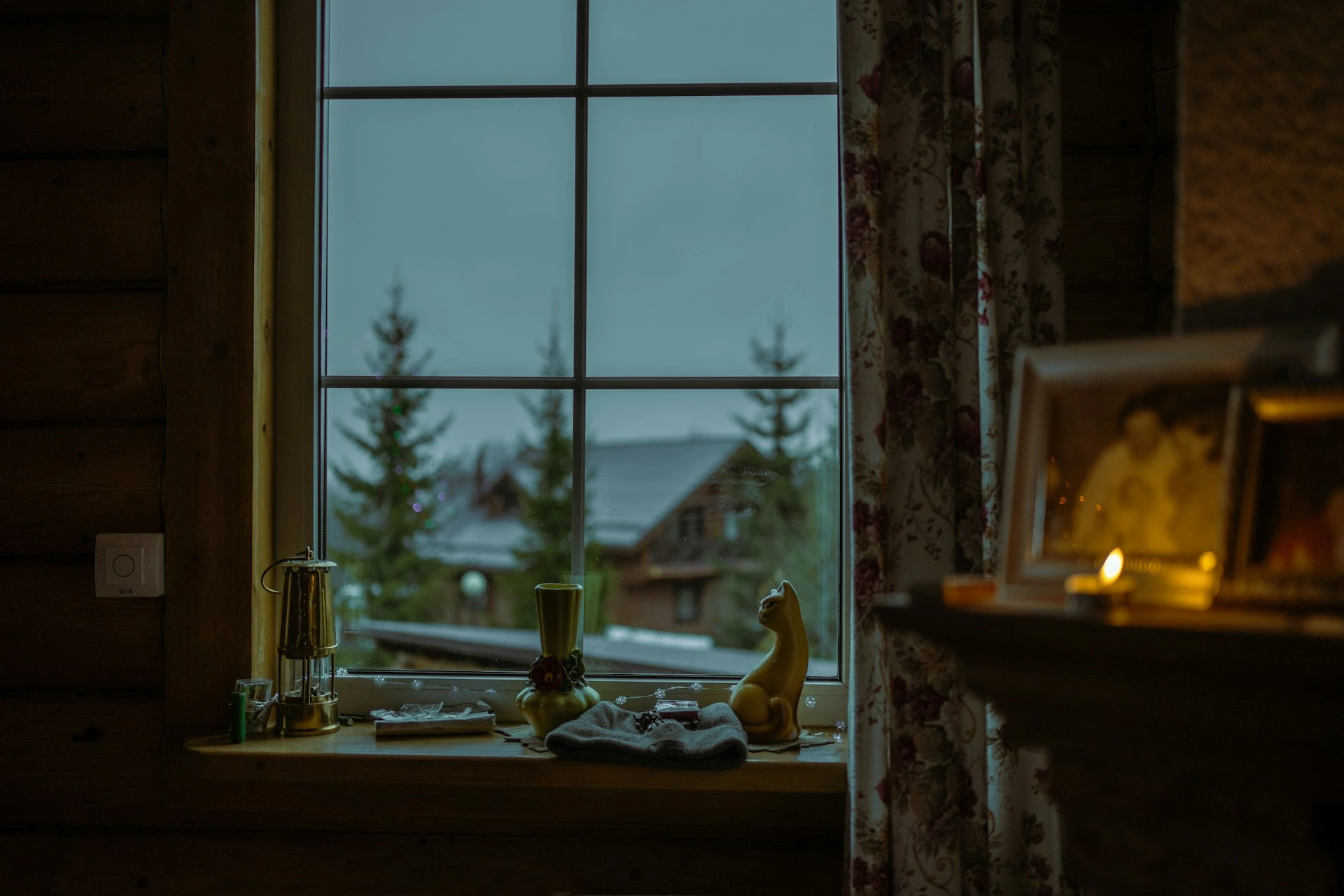 Looking through a Calgary cabin window on a snowy evening with soft indoor light.