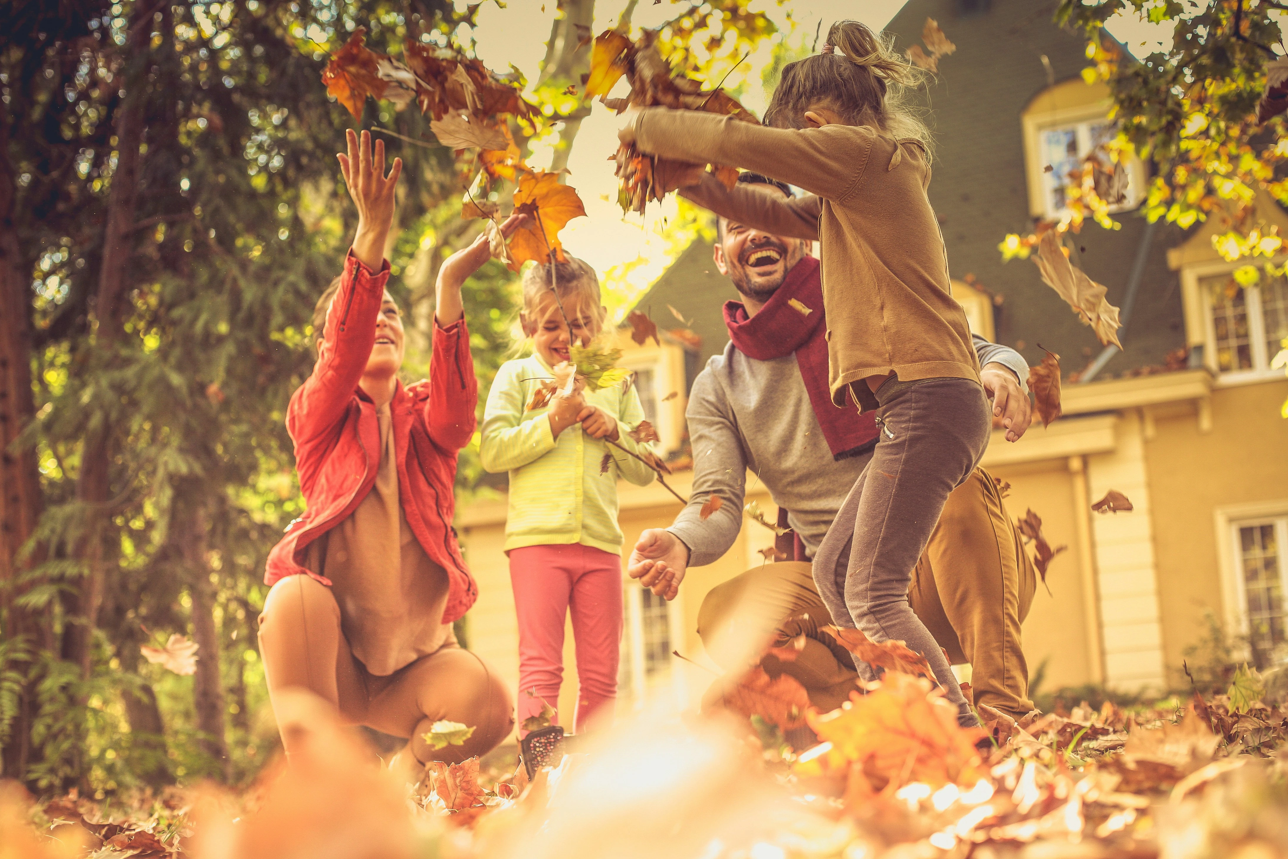 Family playing with autumn leaves outside their Calgary home.