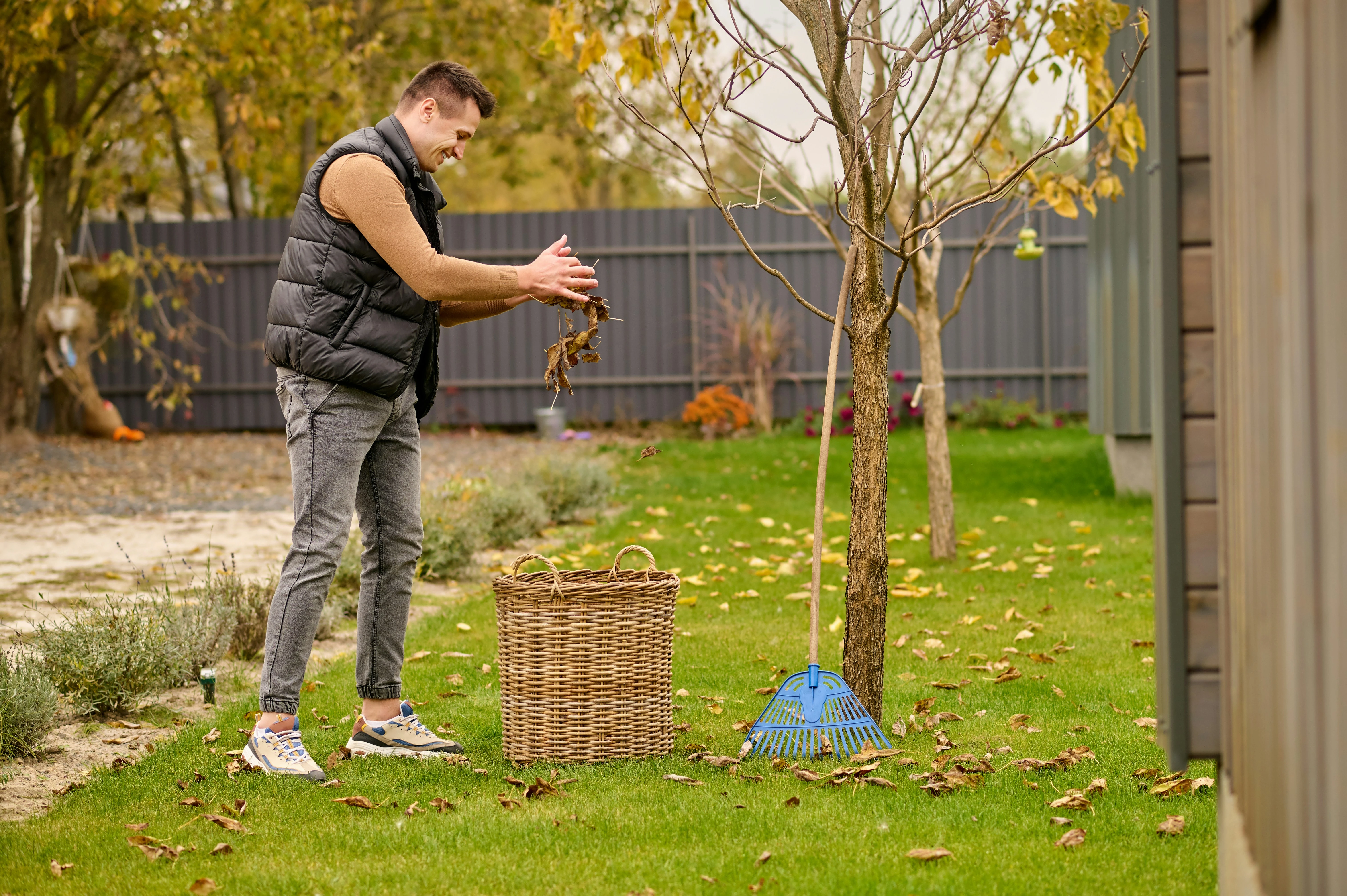 Calgary homeowner raking autumn leaves in backyard