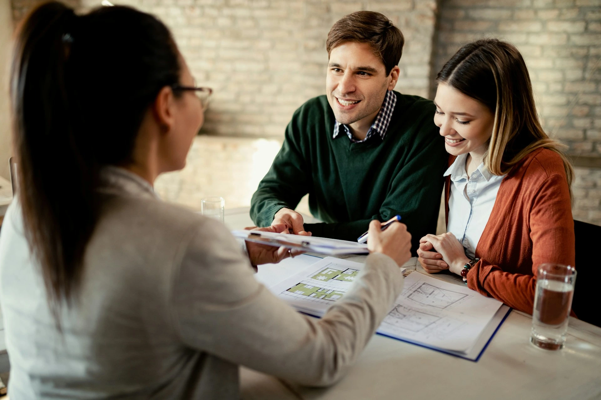Couple meeting with a real estate agent to discuss buying or selling a Calgary home during the winter season.