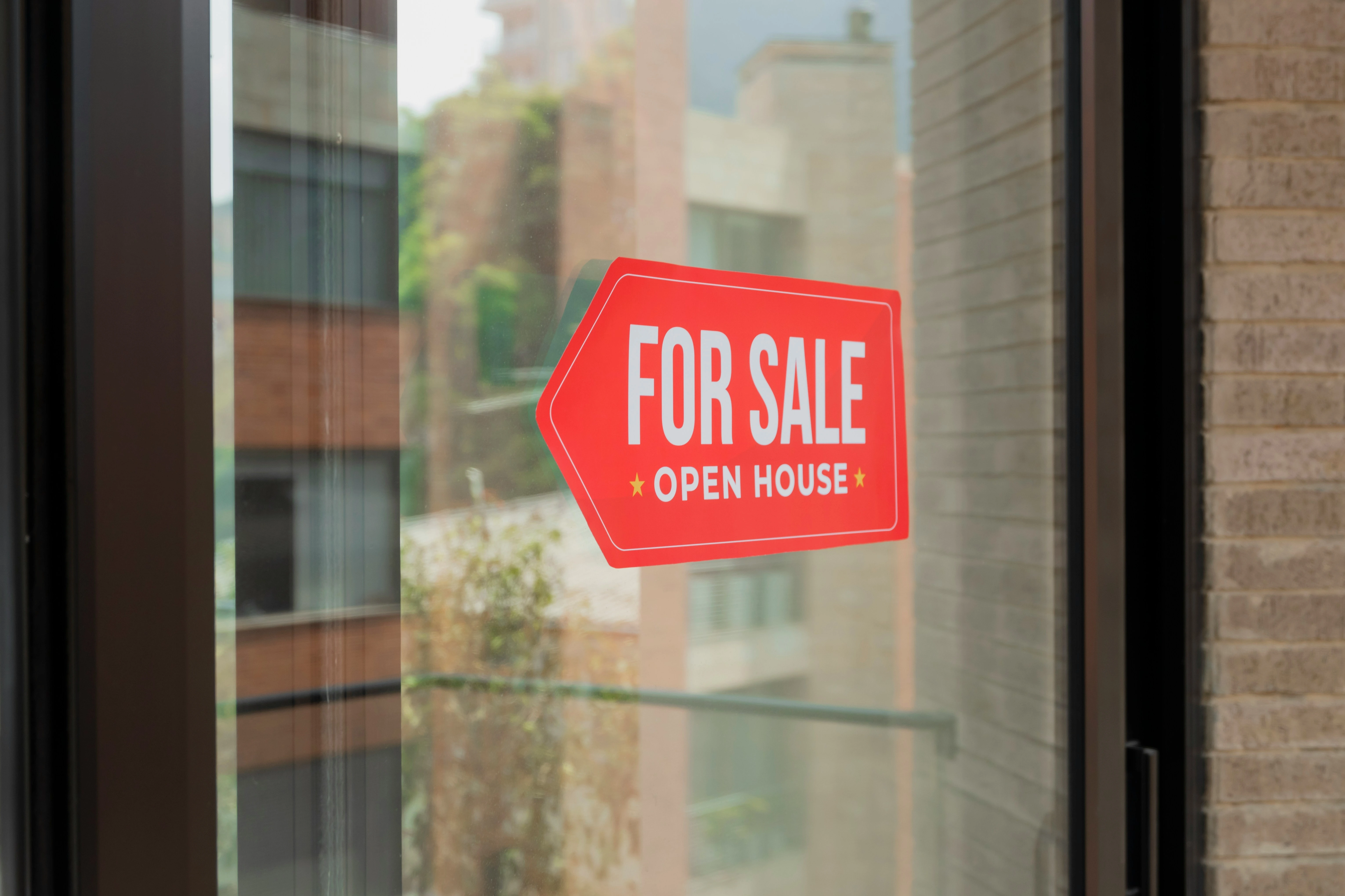 Red "For Sale Open House" sign on a Calgary property window.