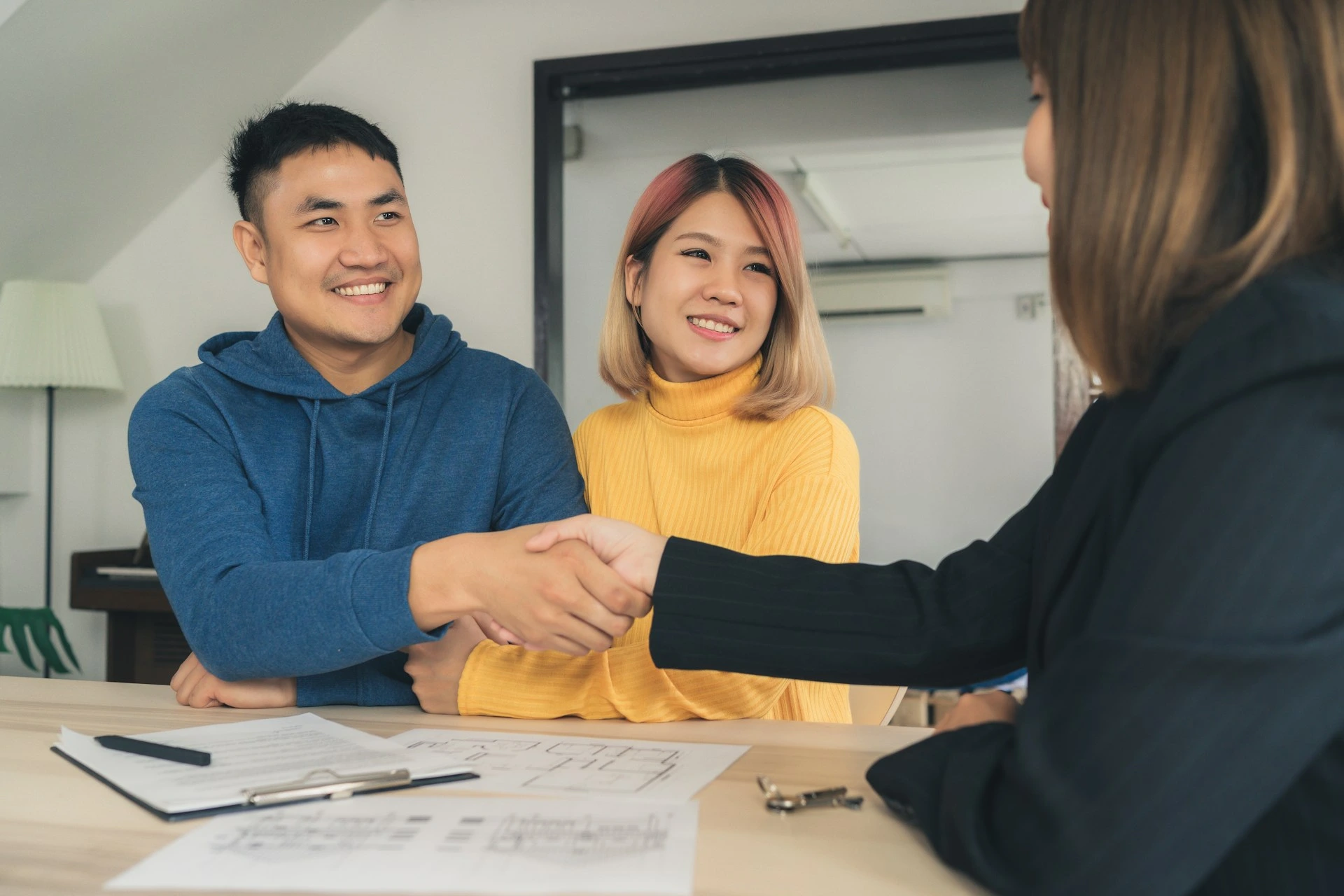 Couple meeting with a mortgage advisor and shaking hands after discussing mortgage pre-approval questions in Calgary.