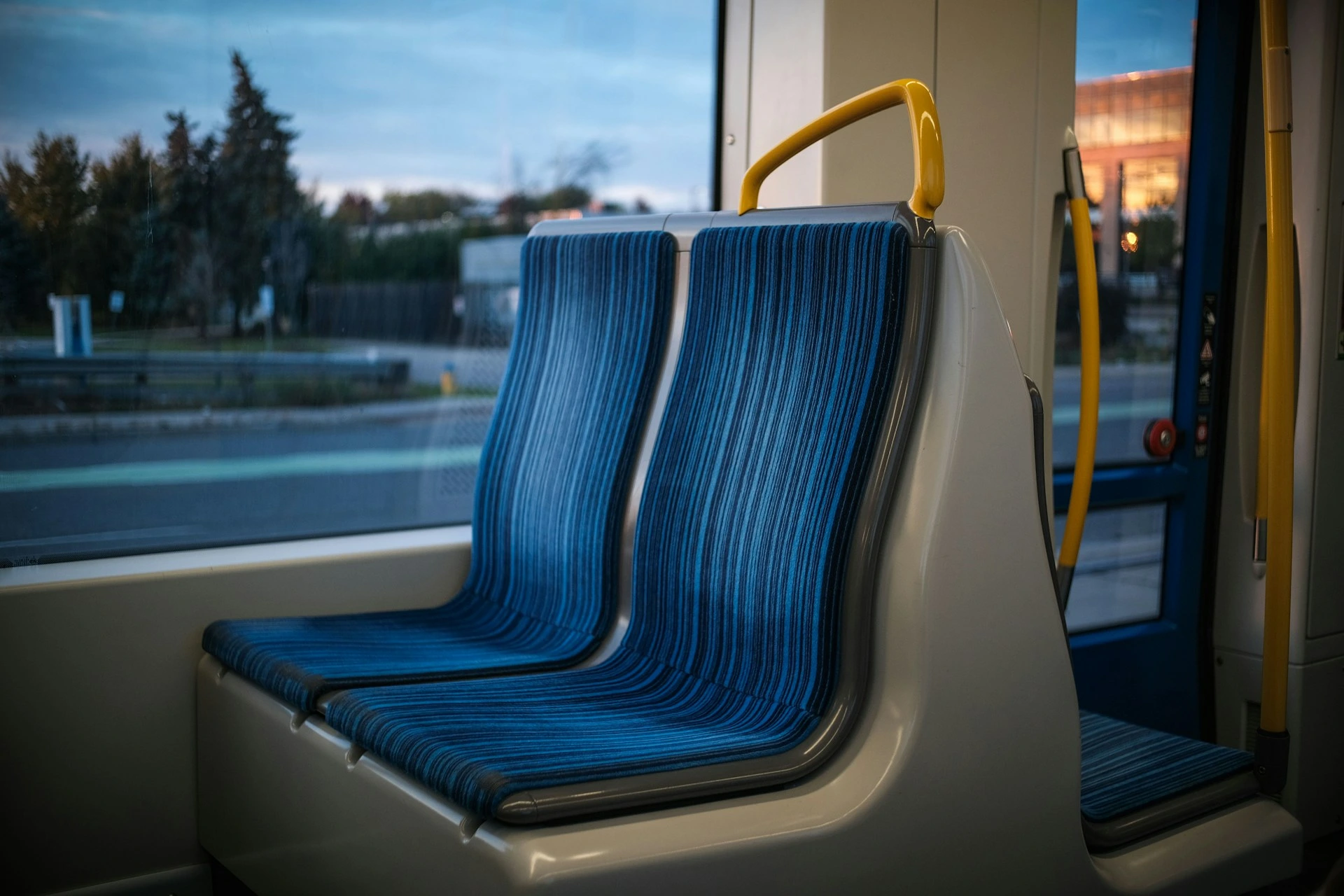 Empty blue seats inside a Calgary C-Train with view through the window.