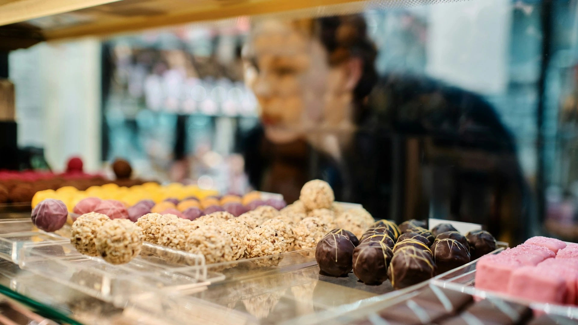 Woman browsing sweets at a bakery counter, representing the local shops and amenities available near Dalhousie Station in Calgary.