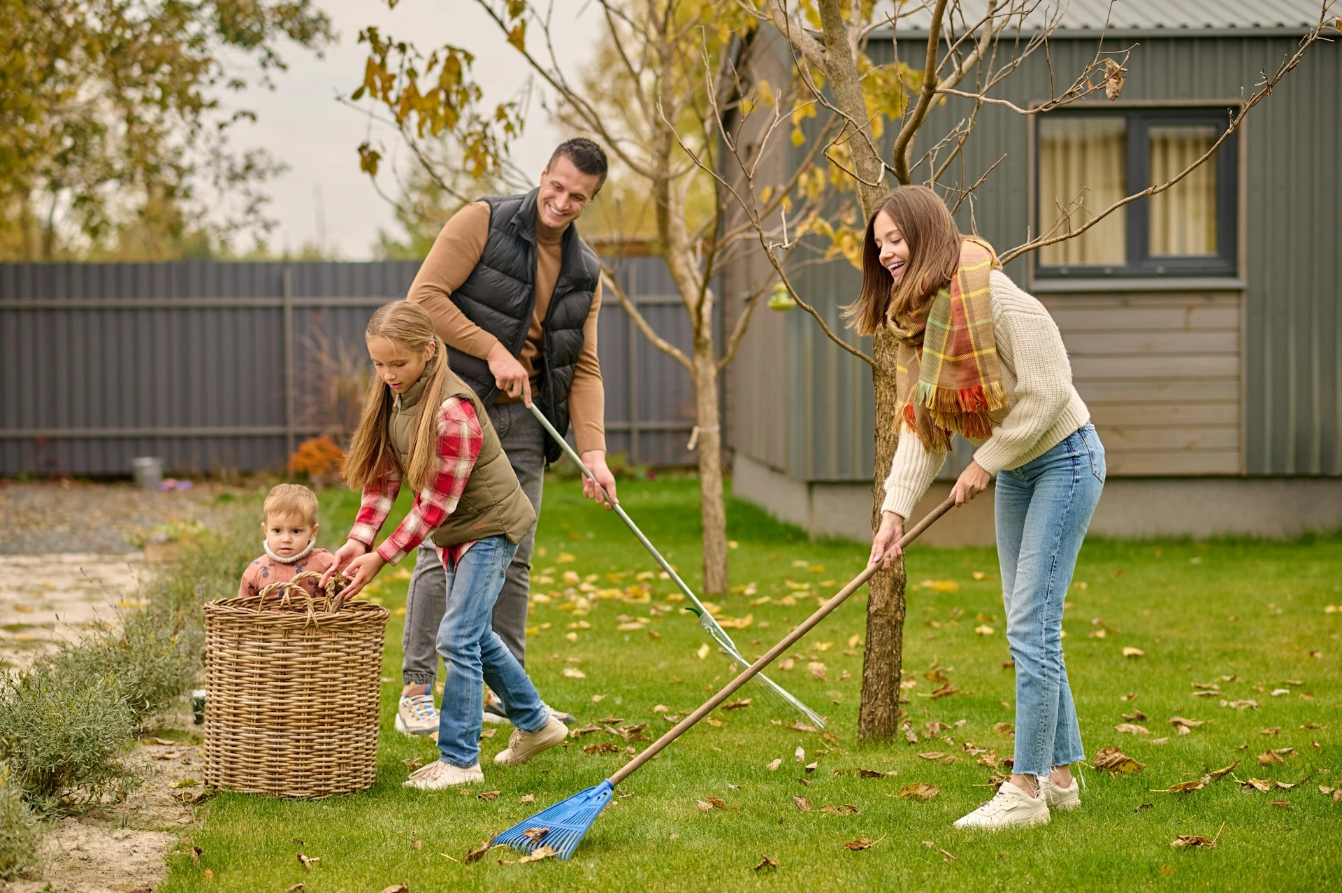 Family raking leaves in backyard of Calgary home, preparing outdoor spaces for fall home selling.