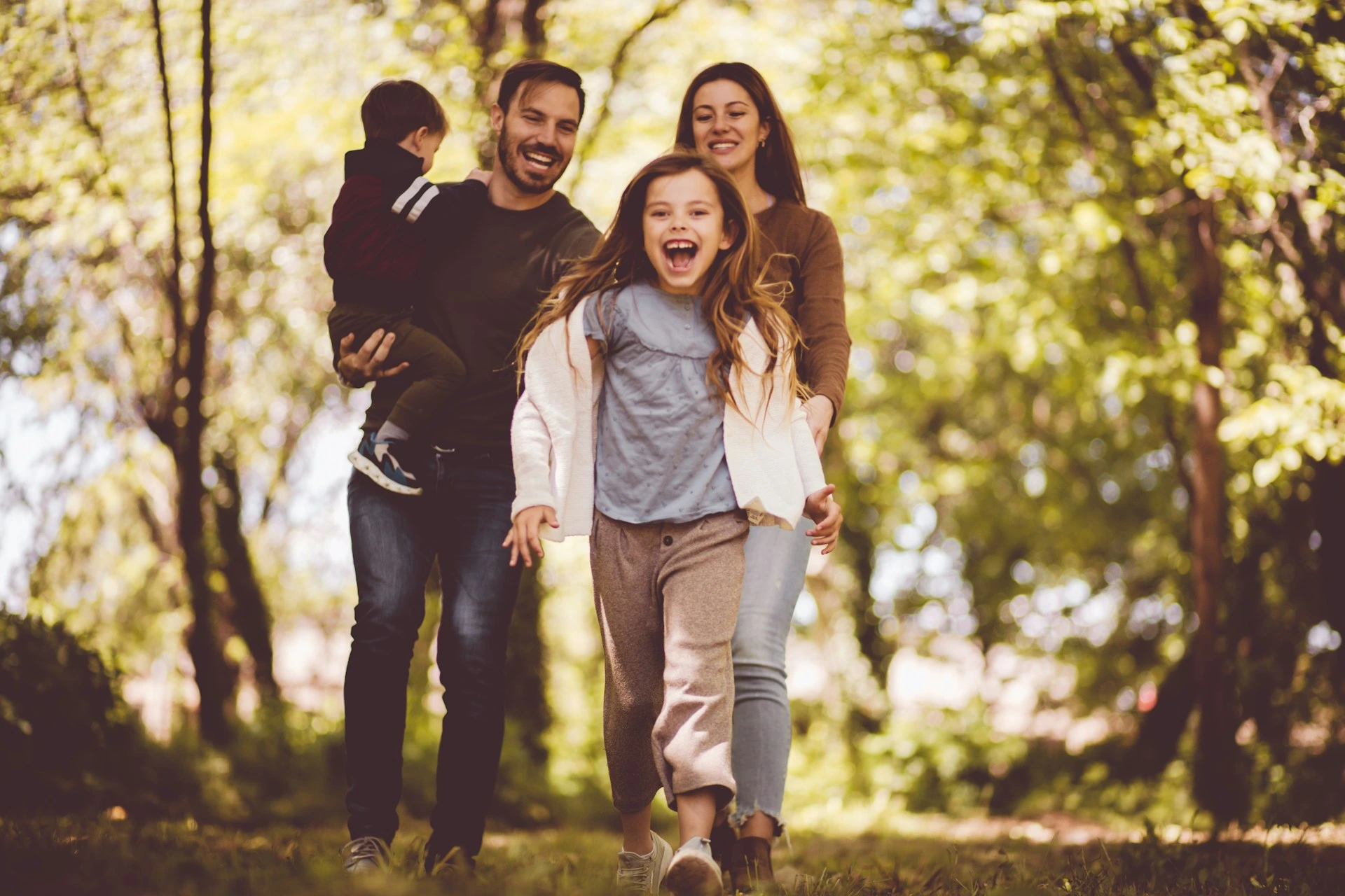Family enjoying a walk through a park surrounded by trees in the Charleswood Calgary neighbourhood.