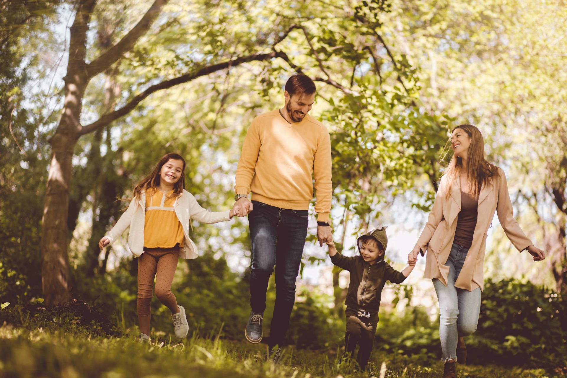 Family walking together on a sunny trail in Citadel, Calgary, enjoying the neighbourhood&rsquo;s natural surroundings.
