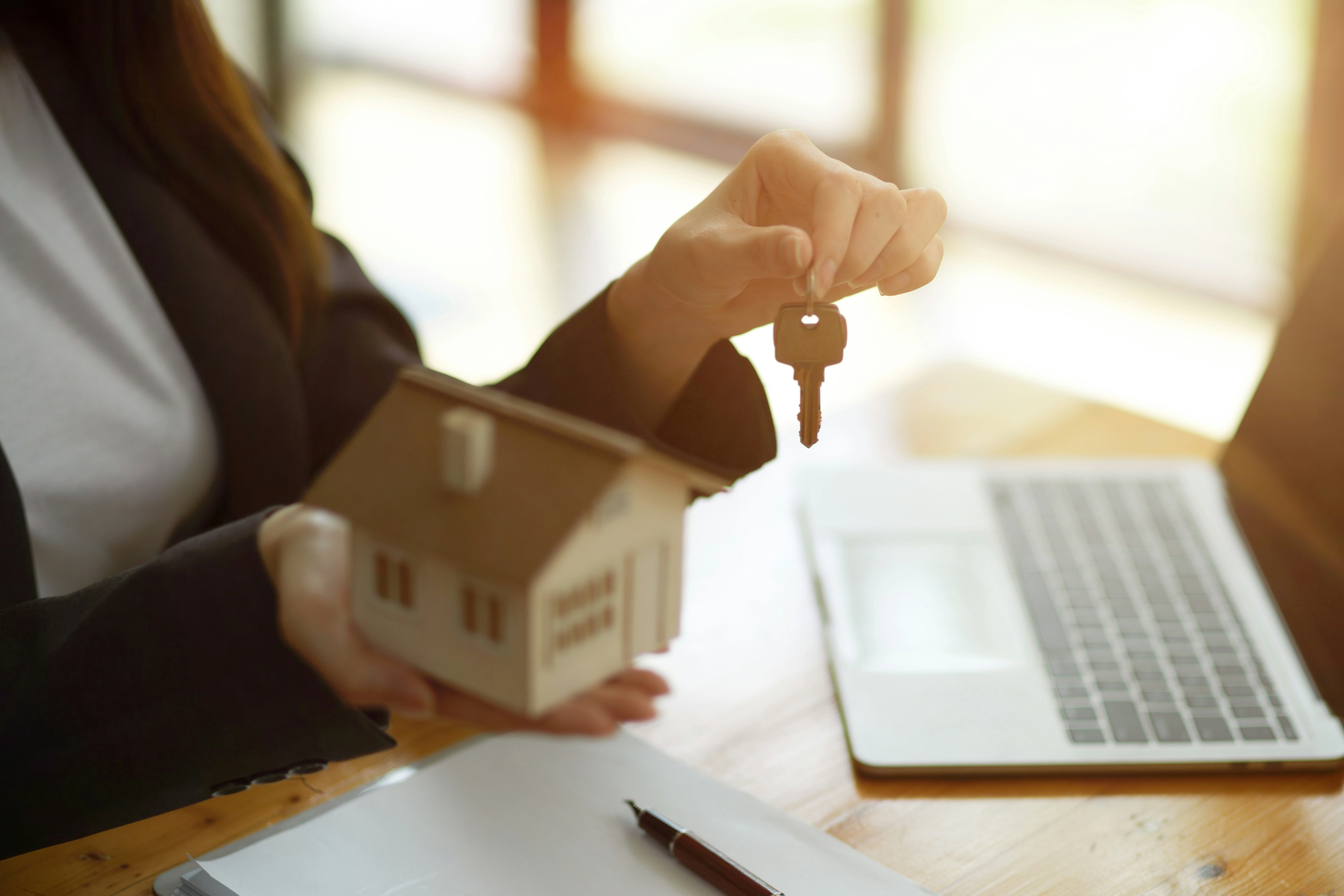 Real estate agent handing over keys with a house model, representing affordable home ownership in Calgary.
