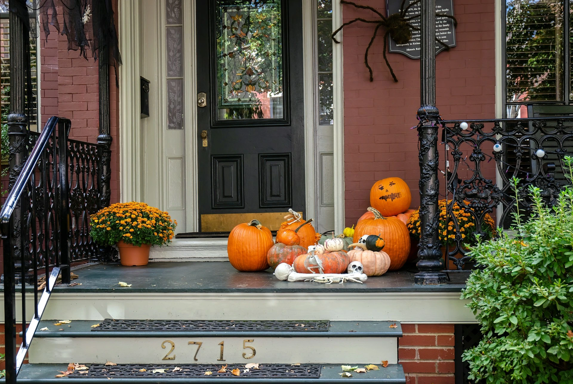 Front porch of a Calgary home decorated with pumpkins, flowers, and Halloween props.