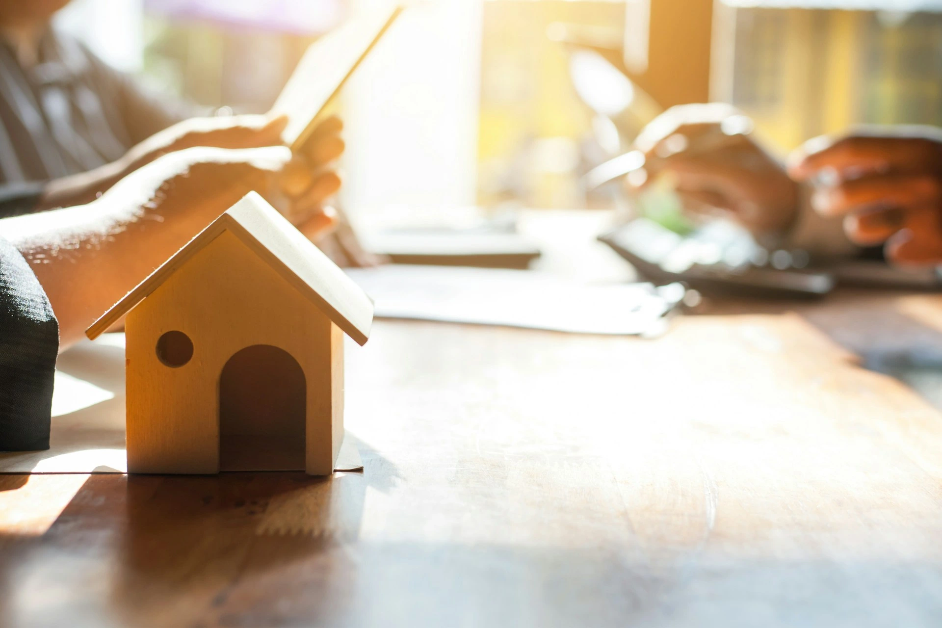 Close-up of a home model on a table with people discussing real estate plans in Calgary.