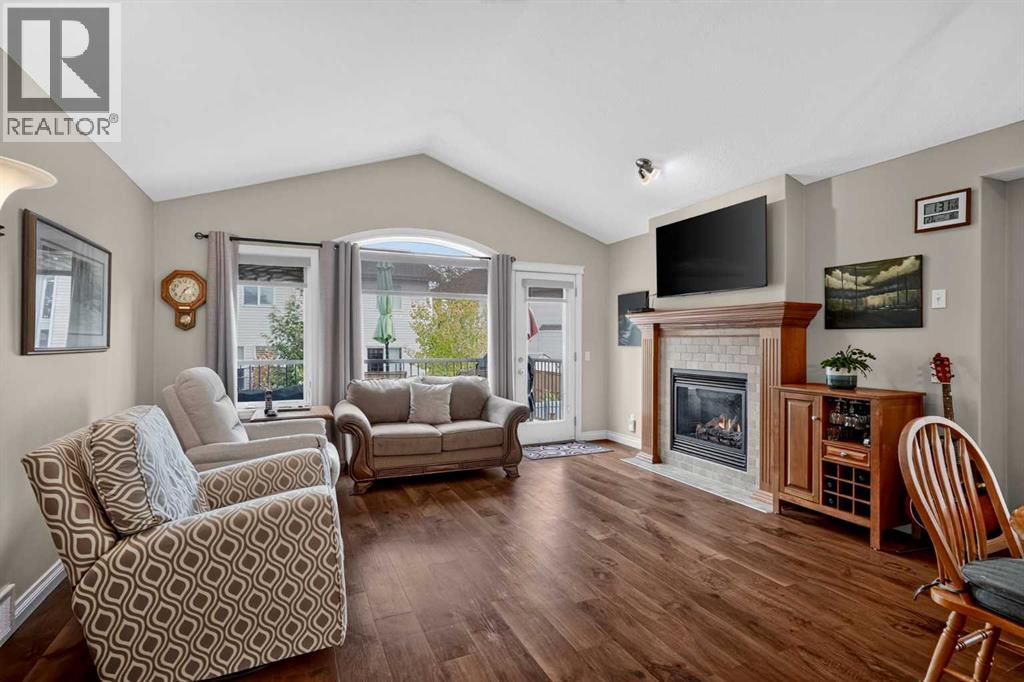 Bright living room with vaulted ceilings and stone gas fireplace at 226 Cimarron Drive, Okotoks