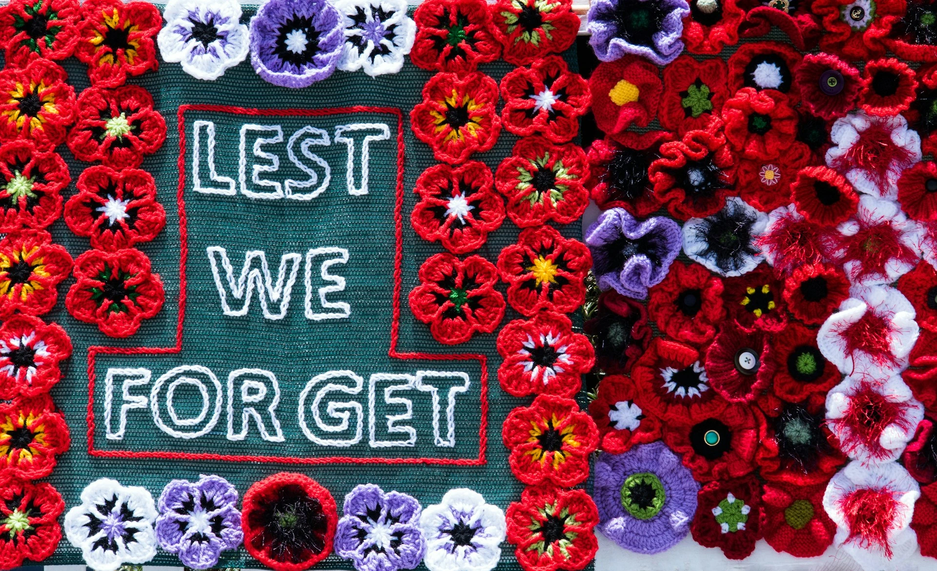 Crocheted red poppies surrounding a &ldquo;Lest We Forget&rdquo; message, symbolizing Remembrance Day in Calgary.
