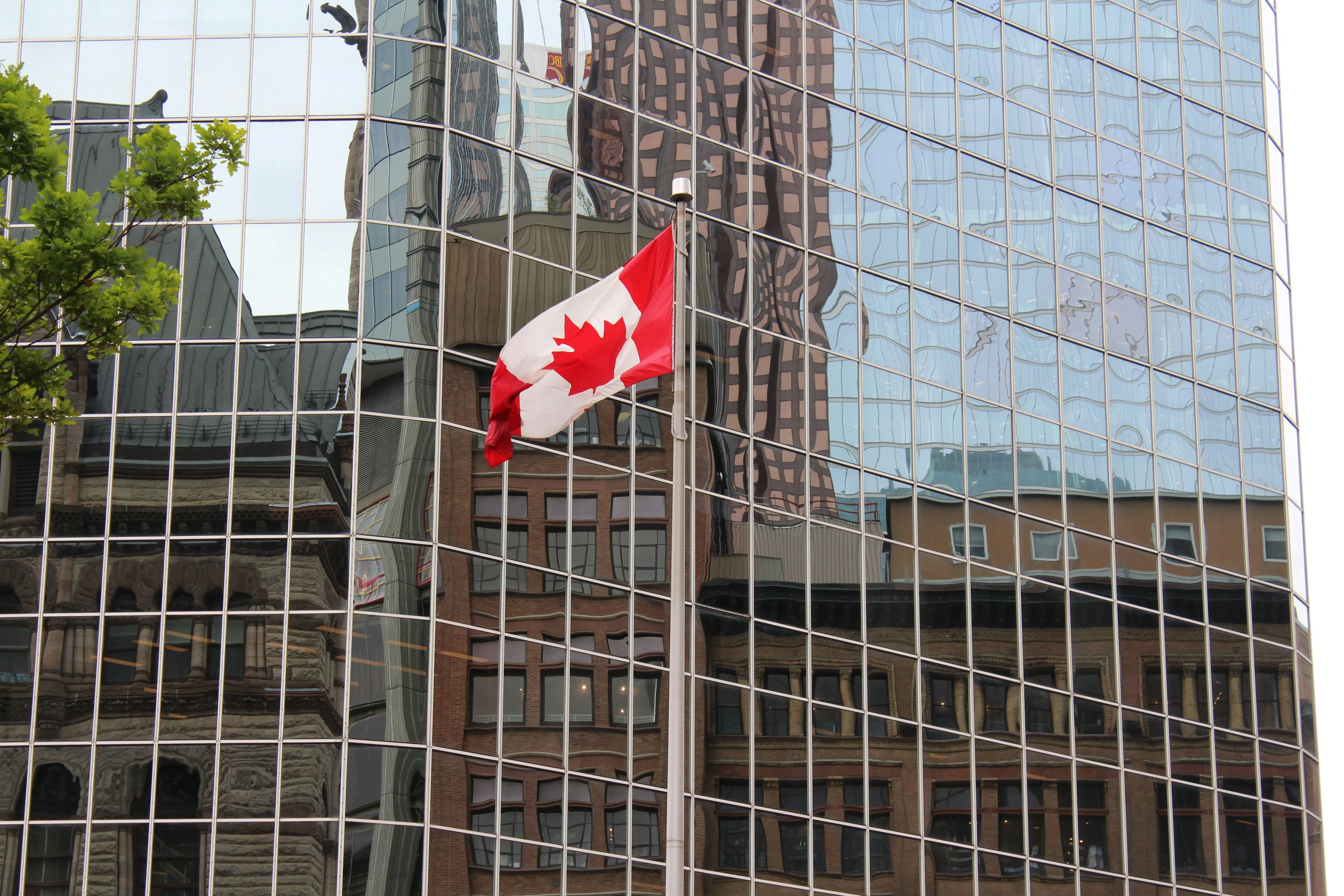 Canadian flag in front of office buildings, symbolizing Bank of Canada interest rate decisions in 2025.