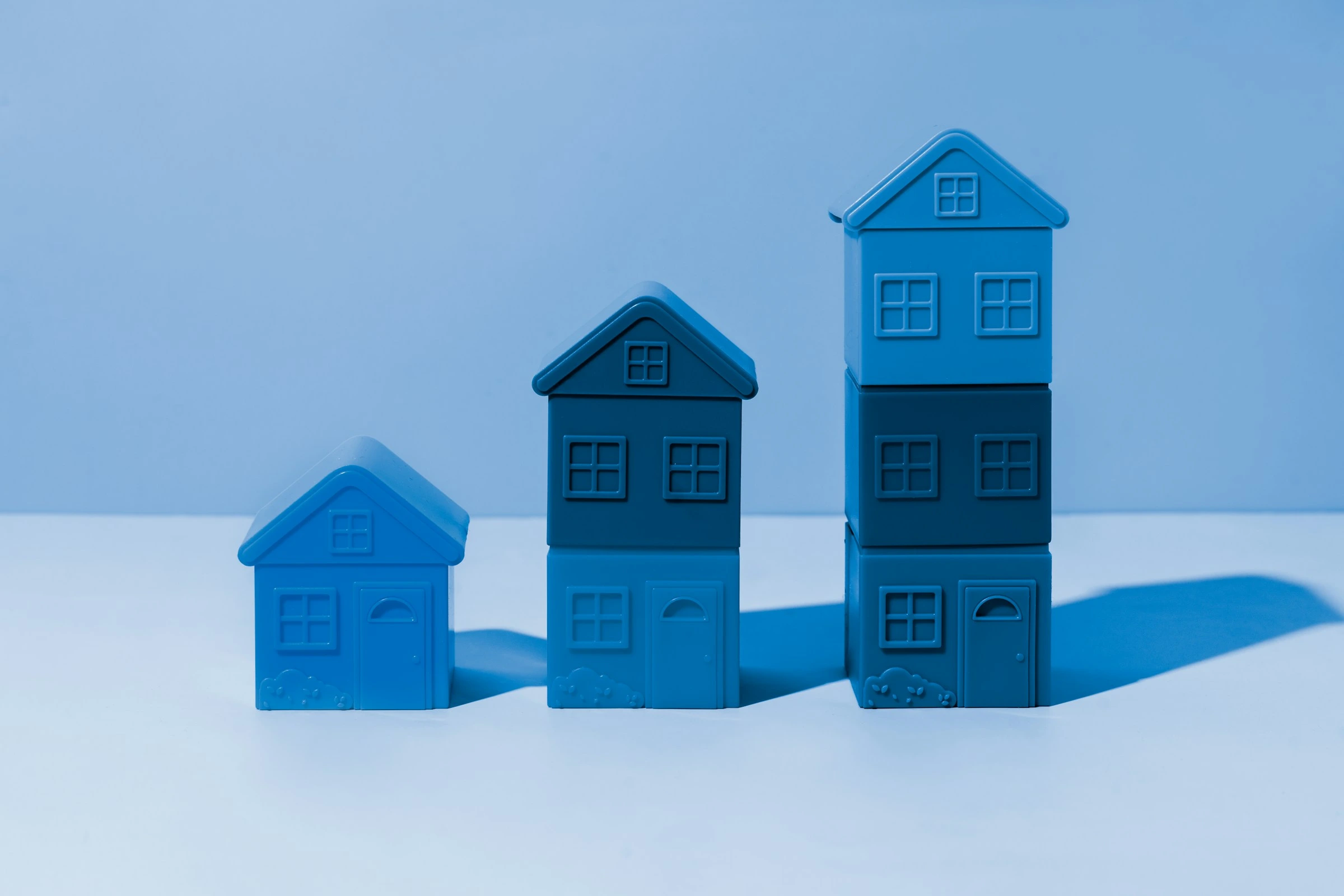 Blue wooden house models on a desk symbolizing Calgary real estate market summary for August 2025