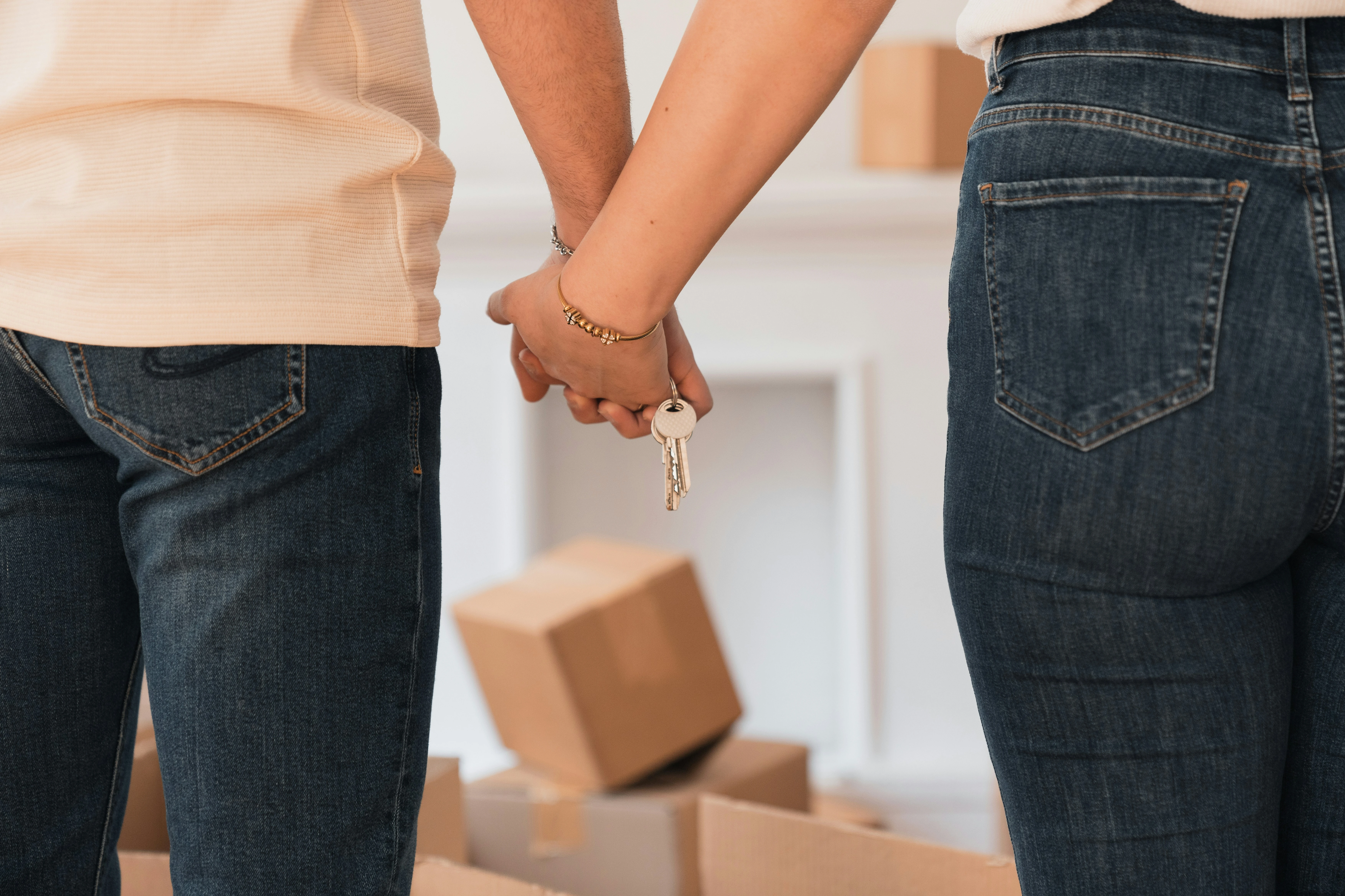 Couple holding house keys with moving boxes in the background, symbolizing Calgary townhome purchase in 2025.