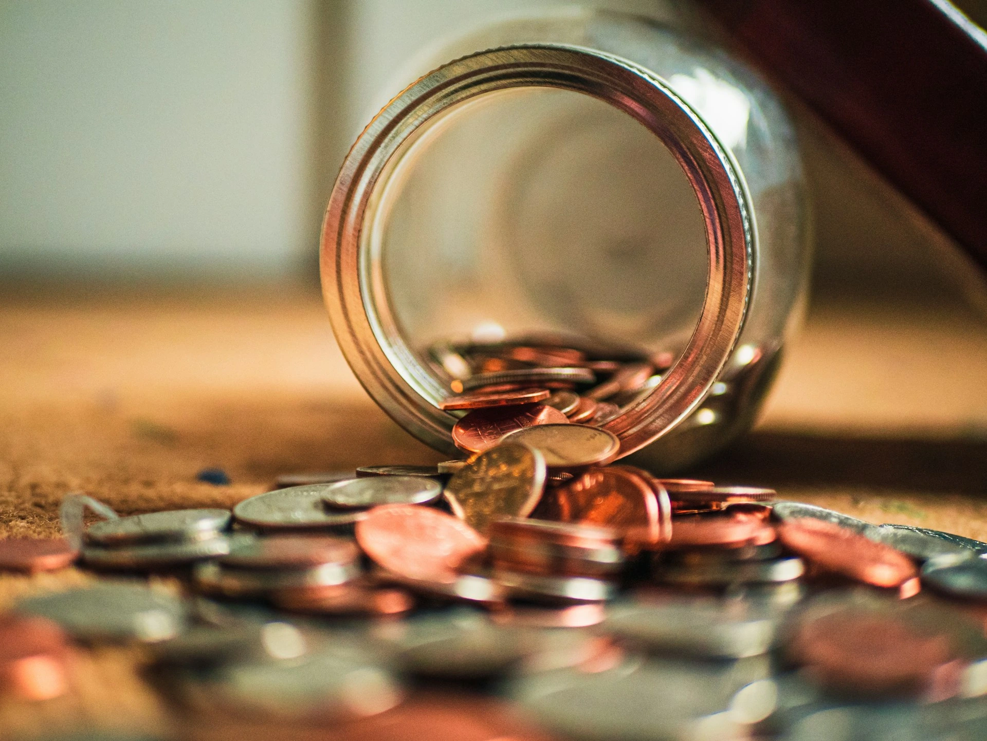 Spilled coins from a jar symbolizing hidden costs and unexpected expenses in buying a Calgary home.